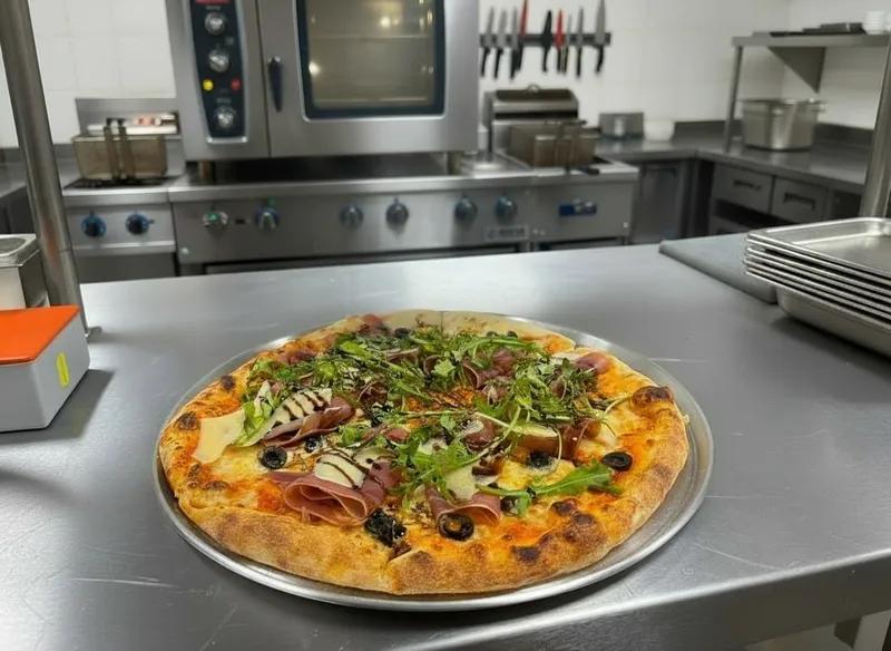 Pizza de jamón serrano, aceitunas, parmesano y arúgula