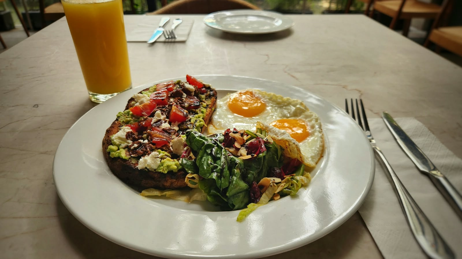 Toast de aguacate con queso de cabra, jitomate y huevos
